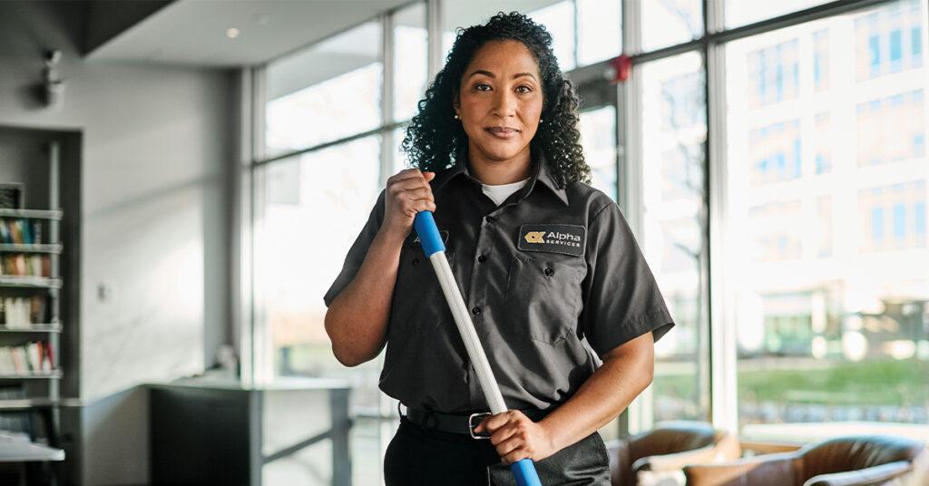 Woman standing in restaurant holding a mop with a serious face