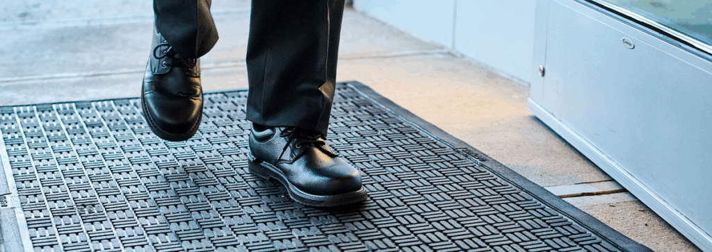 Close-up of staff standing on a UniFirst scraper mat at the entry of a building