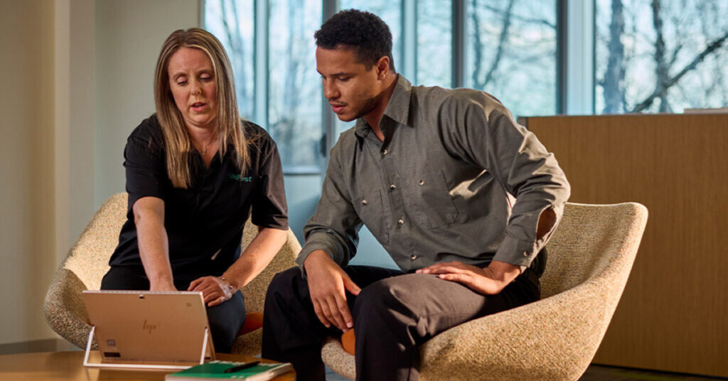 A UniFirst representative sits with a customer at a tablet