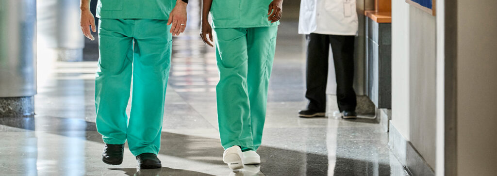 Healthcare industry workers walking the halls of a hospital wearing UniFirst scrub pants.