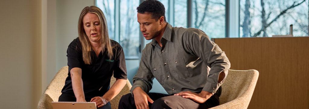 A UniFirst representative sitting with a customer discussing work uniform rental service in an office setting