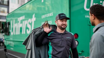 RSR standing with a customer in front of a UniFirst truck discussing uniform rental services
