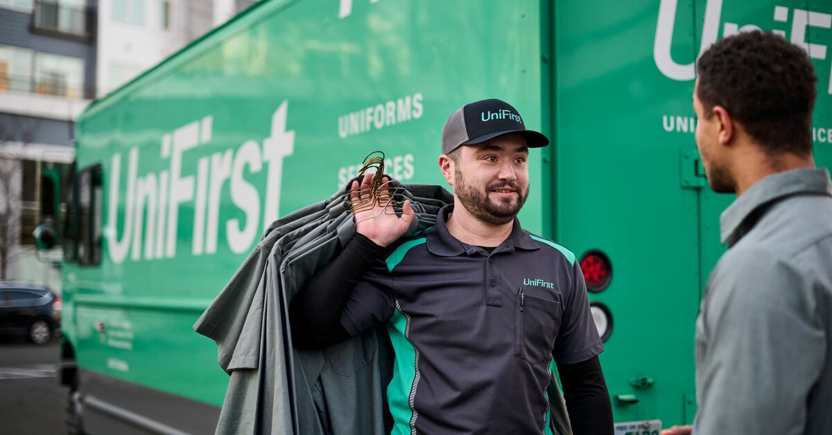 RSR standing with a customer in front of a UniFirst truck discussing uniform rental services