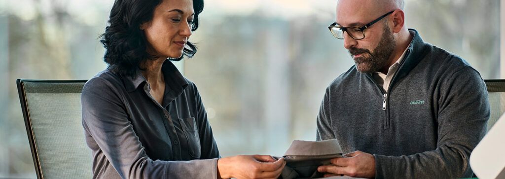 A UniFirst Representative and customer looking at a garment and discussing uniform rental services
