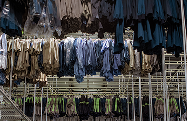 Countless workwear uniforms hanging inside a UniFirst location ready for delivery with a uniform rental service