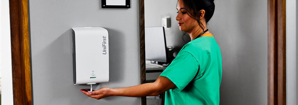 A woman using hand sanitizer to encourage workplace hygiene