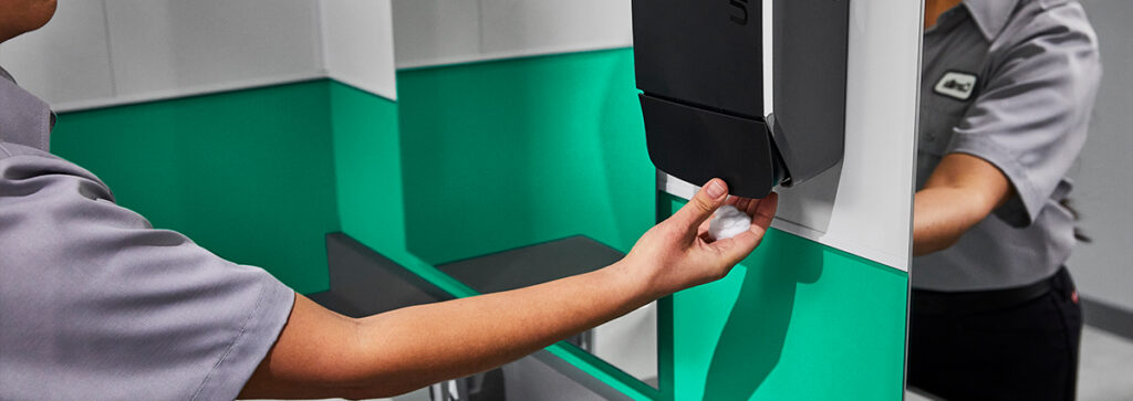 Woman using soap dispenser for good hygiene