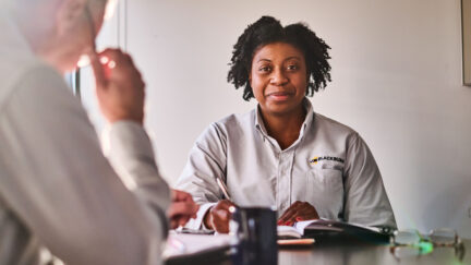 A woman sitting at a table with a professional look in a UniFirst uniform