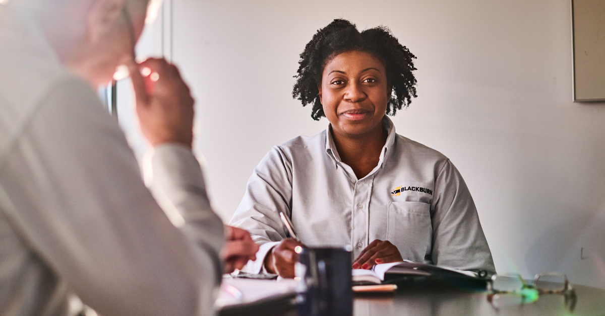 A woman sitting at a table with a professional look in a UniFirst uniform